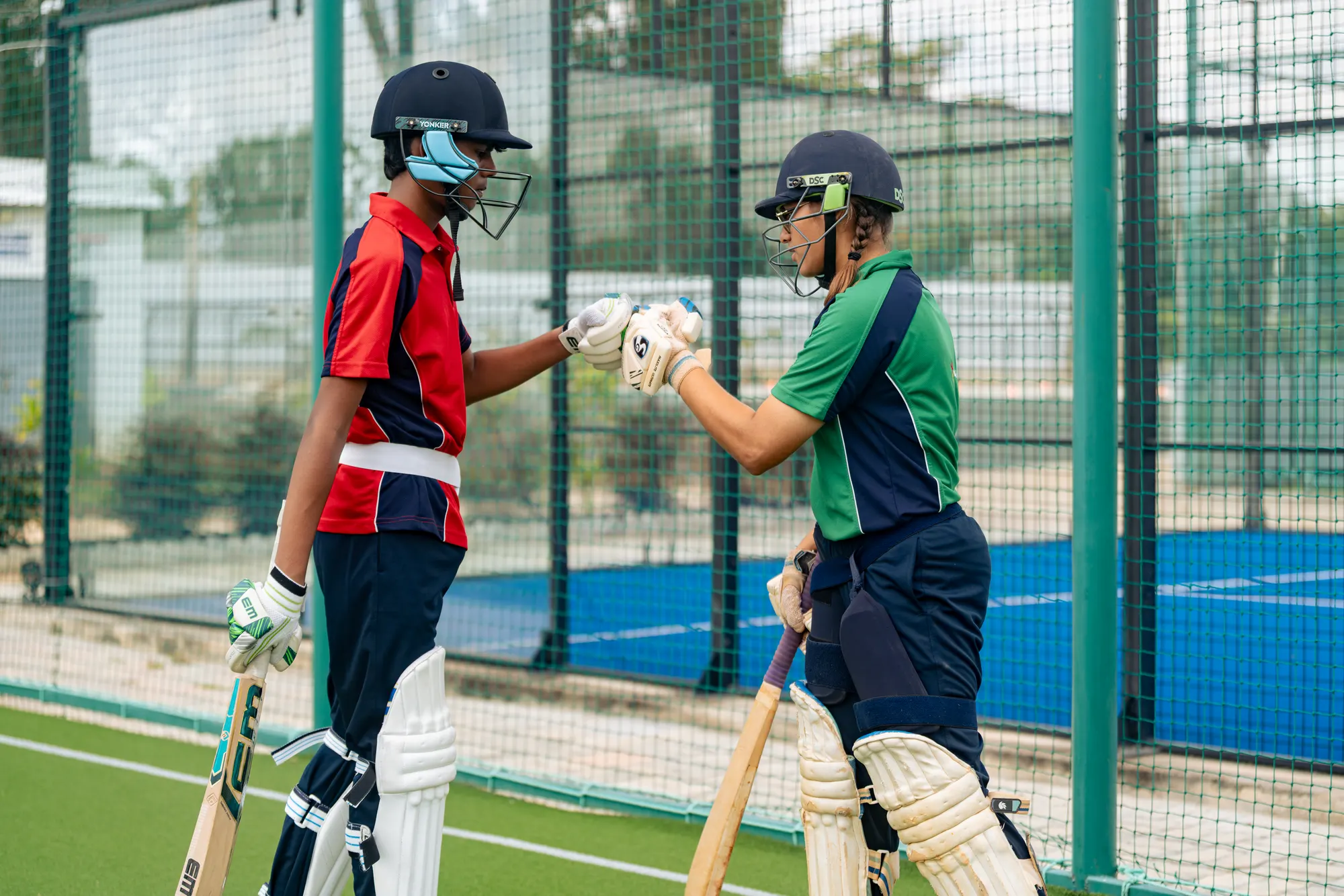 Two Wellsprings students in cricket kit bumping gloves in the nets