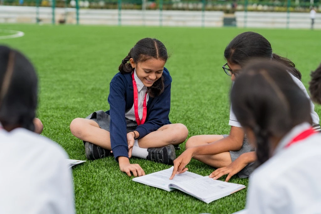 Wellsprings students reading a book together on the field