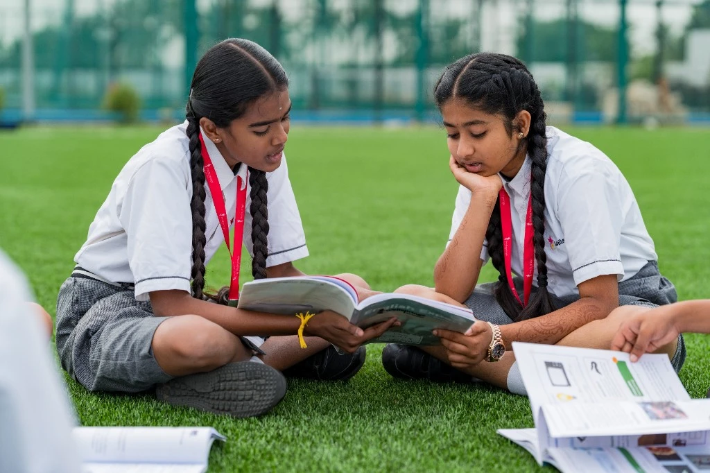 Wellsprings students reading together on the field.