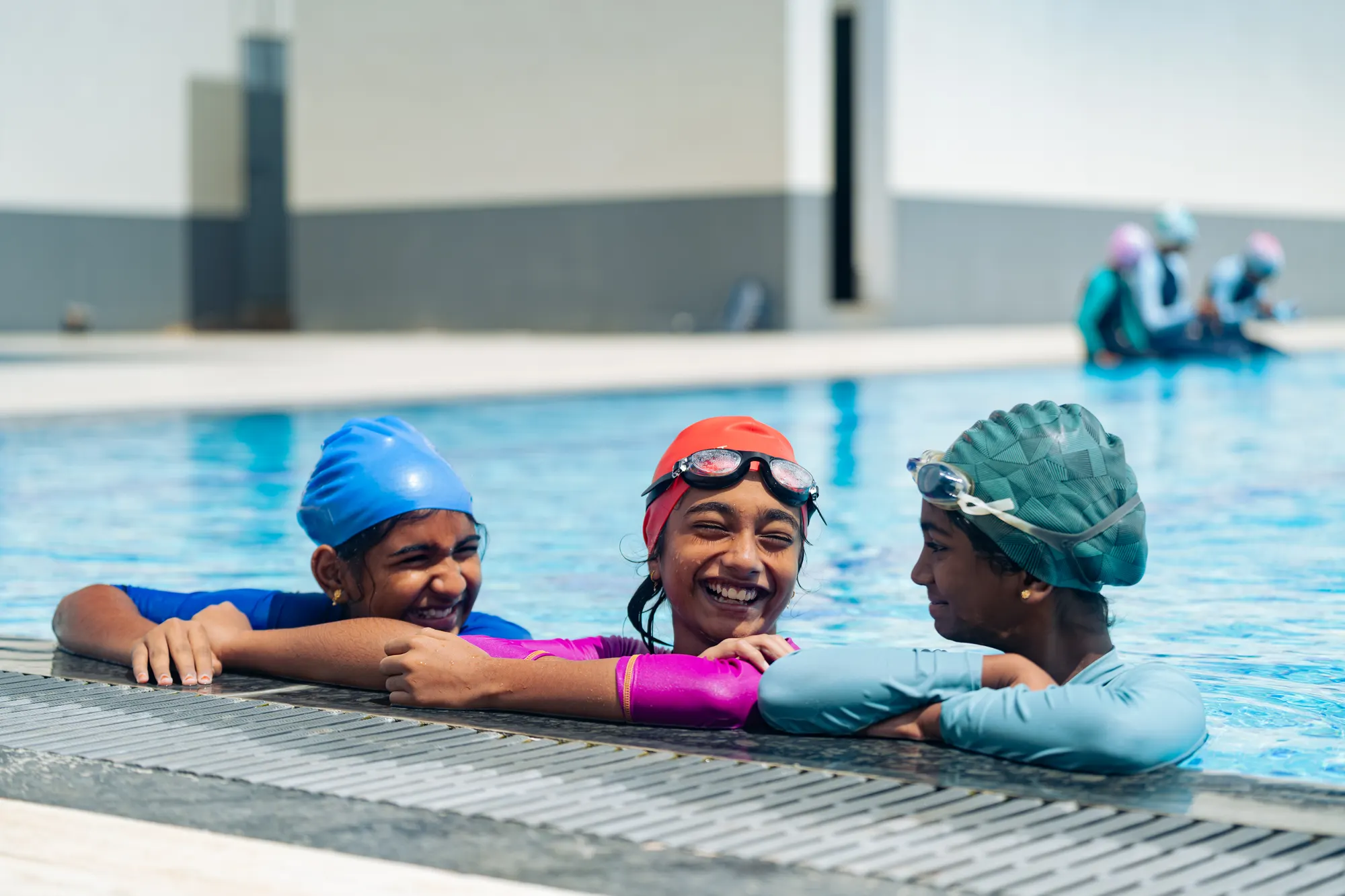 Three Wellsprings students smiling at the edge of the swimming pool